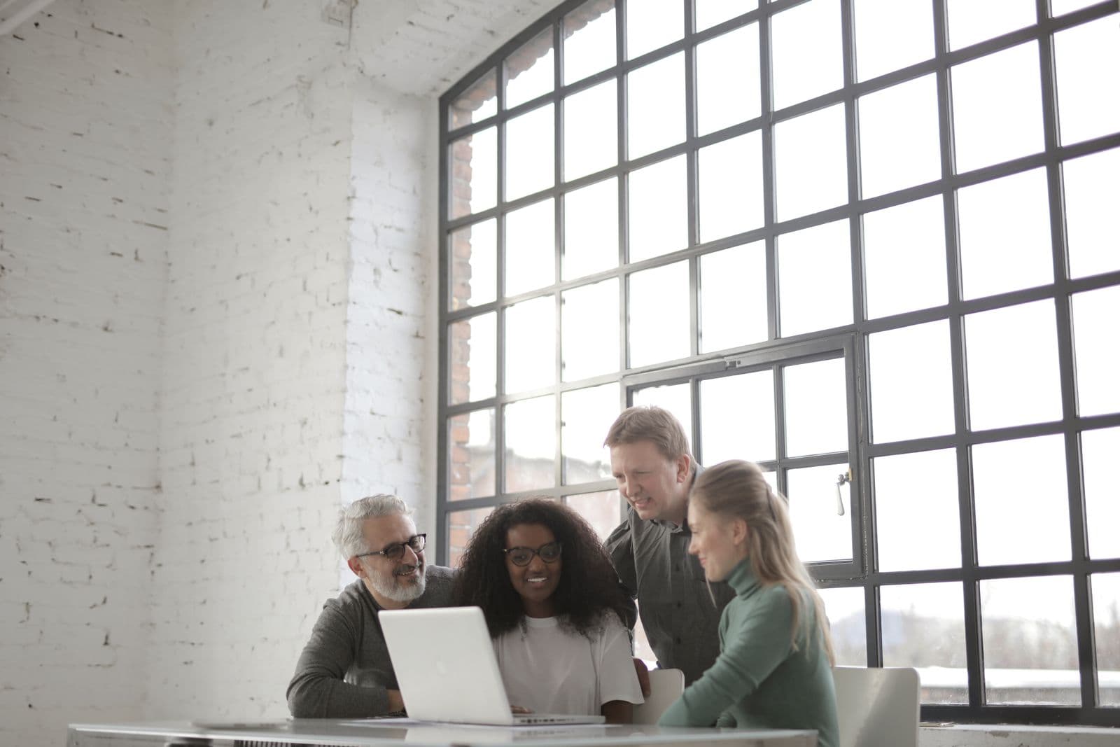 Colleagues working together around a screen in a modern office